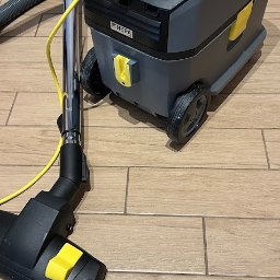 Green Hall Sp. z o.o. - Profesjonalny odkurzacz Karcher z filtrem HEPA na drewnopodobnej podłodze. Widoczna ssawka i wąż. Sprzęt gotowy do użycia, sugerujący usługi porządkowe.