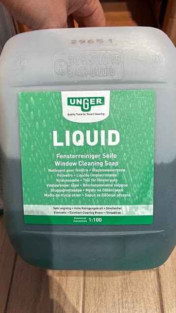 Kanister z płynem do mycia okien marki Unger. Etykieta w kolorze zielonym z napisem 'LIQUID Window Cleaning Soap'. Widoczne napisy w różnych językach.