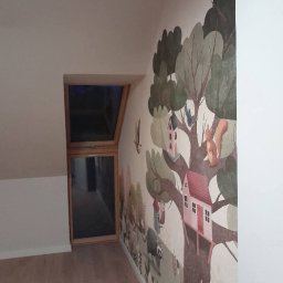 P&K BUD Ewa Kotlińska - Pokój dziecięcy z oknem dachowym i ręcznie malowaną ścianą w bajkowy las. Widoczny fragment podłogi z paneli. Ujęcie z dołu, perspektywa zbieżna.