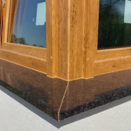 Detale okna z drewnianą ramą i granitowym parapetem zewnętrznym. Precyzyjne wykończenie, widoczna faktura materiałów.