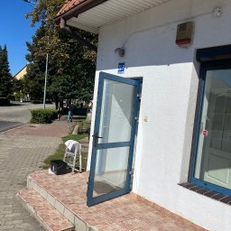 Dziemba Ci Umyje - Otwarta szklana witryna budynku z numerem 22F, drabina z ręcznikiem i wiadro przy wejściu. Usługi czyszczenia witryn sklepowych.