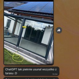 Dziemba Ci Umyje - Mycie szklanego tarasu z panelami słonecznymi na dachu. Żółty wąż i szczotka do mycia szyb leżą na trawie obok czystych, błyszczących szyb.