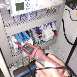 PRĄDPOMISTRZOWSKU - Pomiar napięcia w szafie sterowniczej. Tester napięcia w dłoni elektryka przy listwie zaciskowej z przewodami. Kontroler Eaton easy-E4-DC-12TC1 i inne moduły.