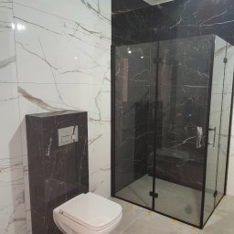 Adam Wierzbicki - Nowoczesna łazienka z kabiną prysznicową typu walk-in, białą toaletą podwieszaną i marmurowymi płytkami w odcieniach bieli i czerni. Minimalistyczny design.