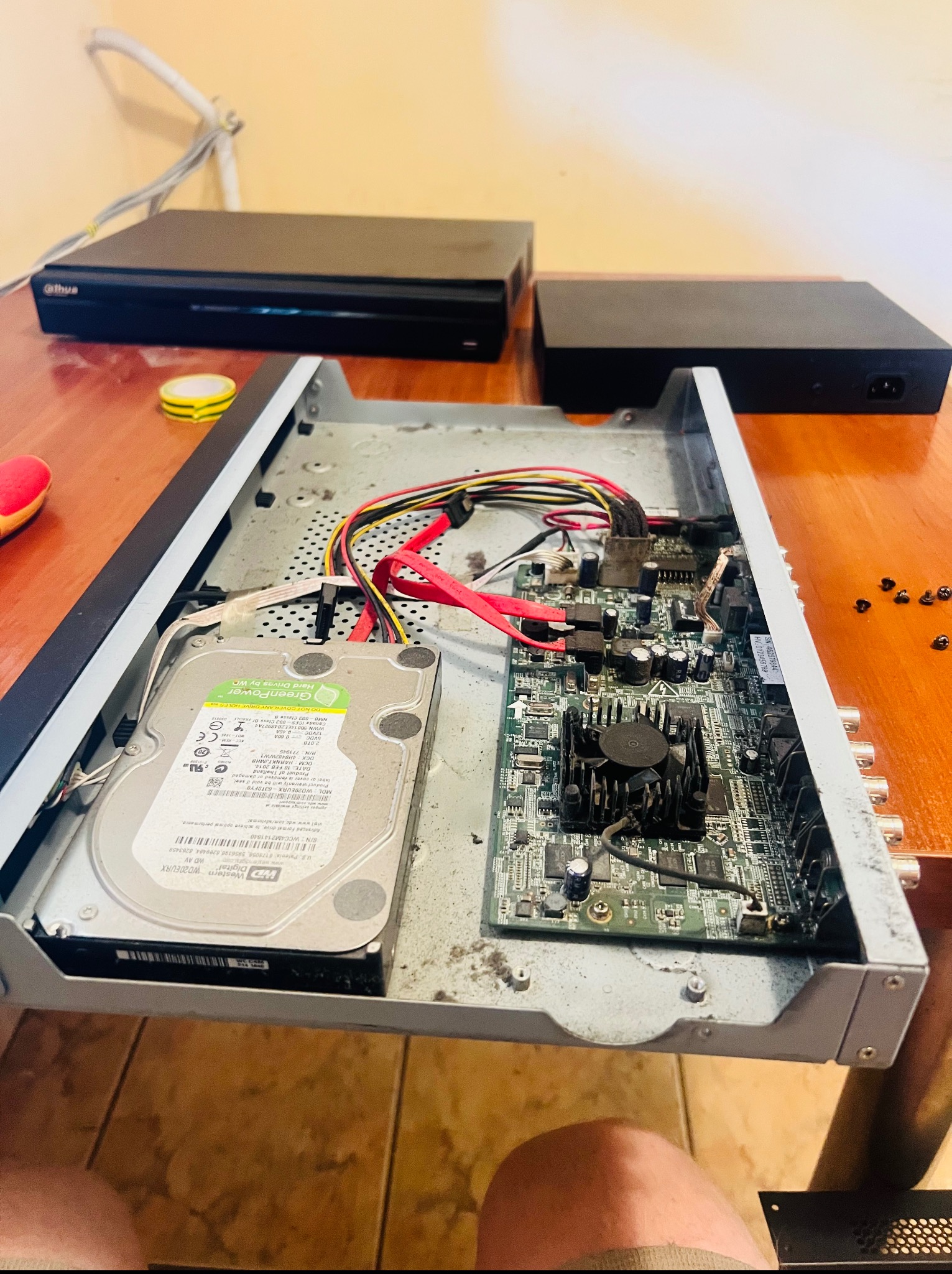 Otwarta obudowa rejestratora CCTV z dyskiem twardym WD Green Power. Widoczne kable, płyta główna i śrubki. Sprzęt monitoringu w trakcie naprawy lub konfiguracji.