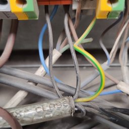 Krzysztof Chorzelewski - Szczegółowe zbliżenie na kolorowe złączki elektryczne z podłączonymi przewodami o różnych kolorach, w tym żółto-zielony przewód uziemiający.
