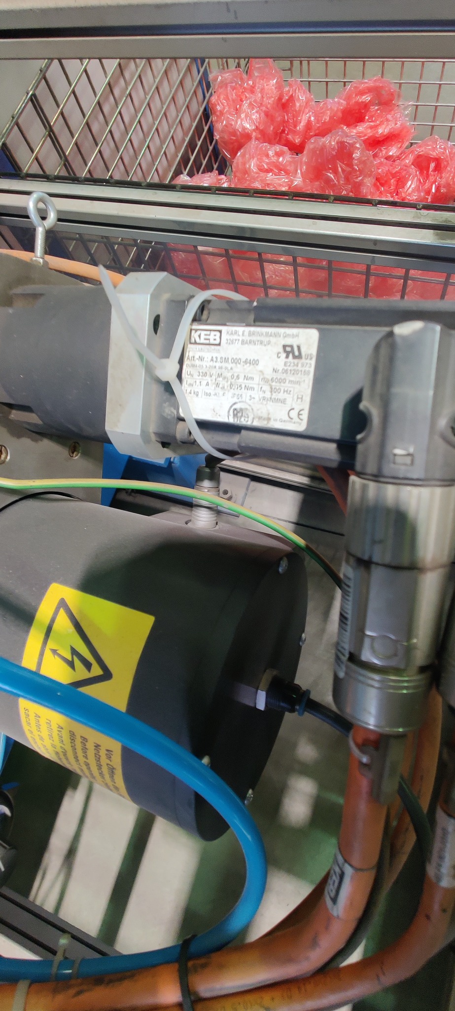 Silnik elektryczny KEB z żółtą naklejką ostrzegawczą i wiązką przewodów w przemysłowym otoczeniu. Widoczna tabliczka znamionowa z danymi technicznymi.