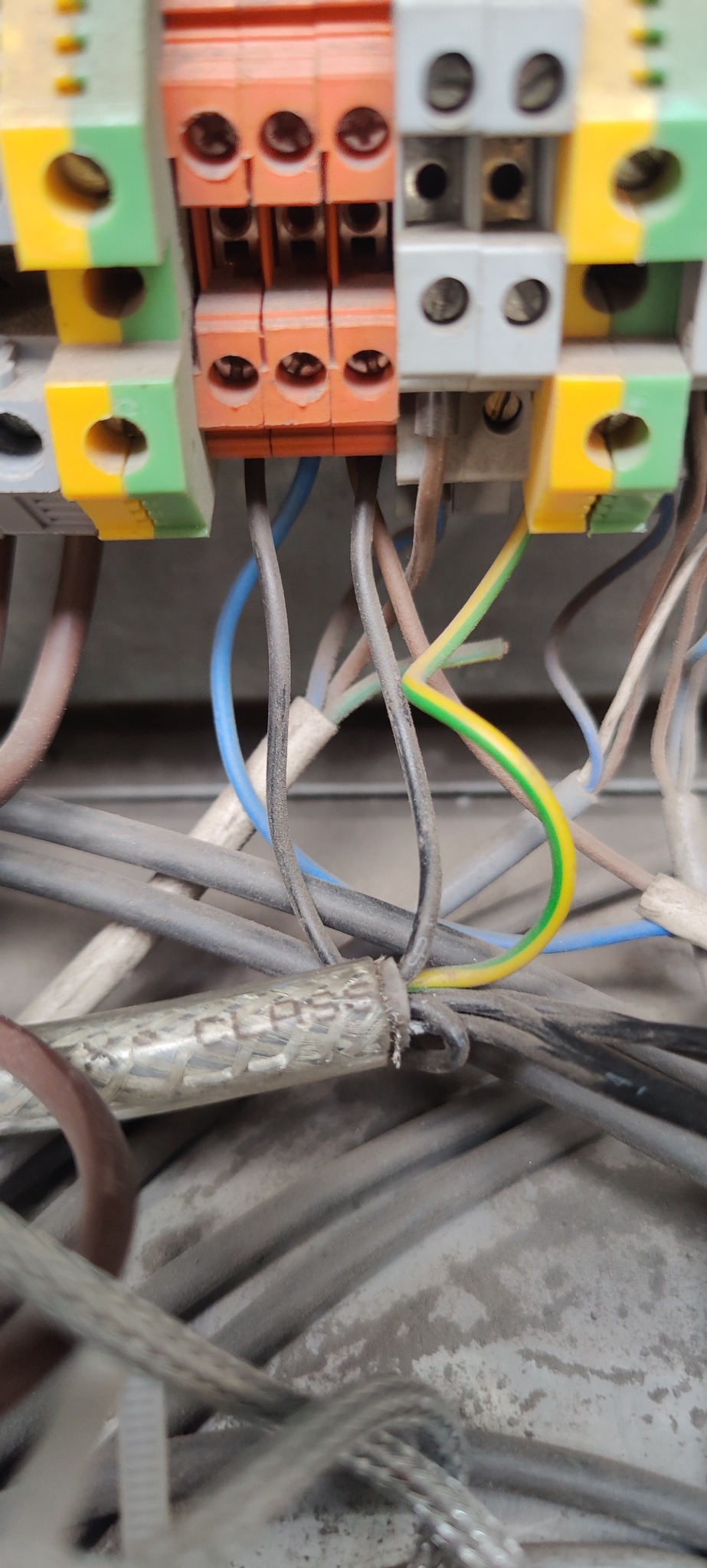 Szczegółowe zbliżenie na kolorowe złączki elektryczne z podłączonymi przewodami o różnych kolorach, w tym żółto-zielony przewód uziemiający.