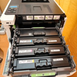 R-TECH ŁUKASZ ROSOWSKI - Otwarta kserokopiarka Brother z wysuniętymi czterema pojemnikami na tonery: czarnym, żółtym, magenta i cyjan. Widoczne etykiety z oznaczeniami kolorów i numerami seryjnymi.