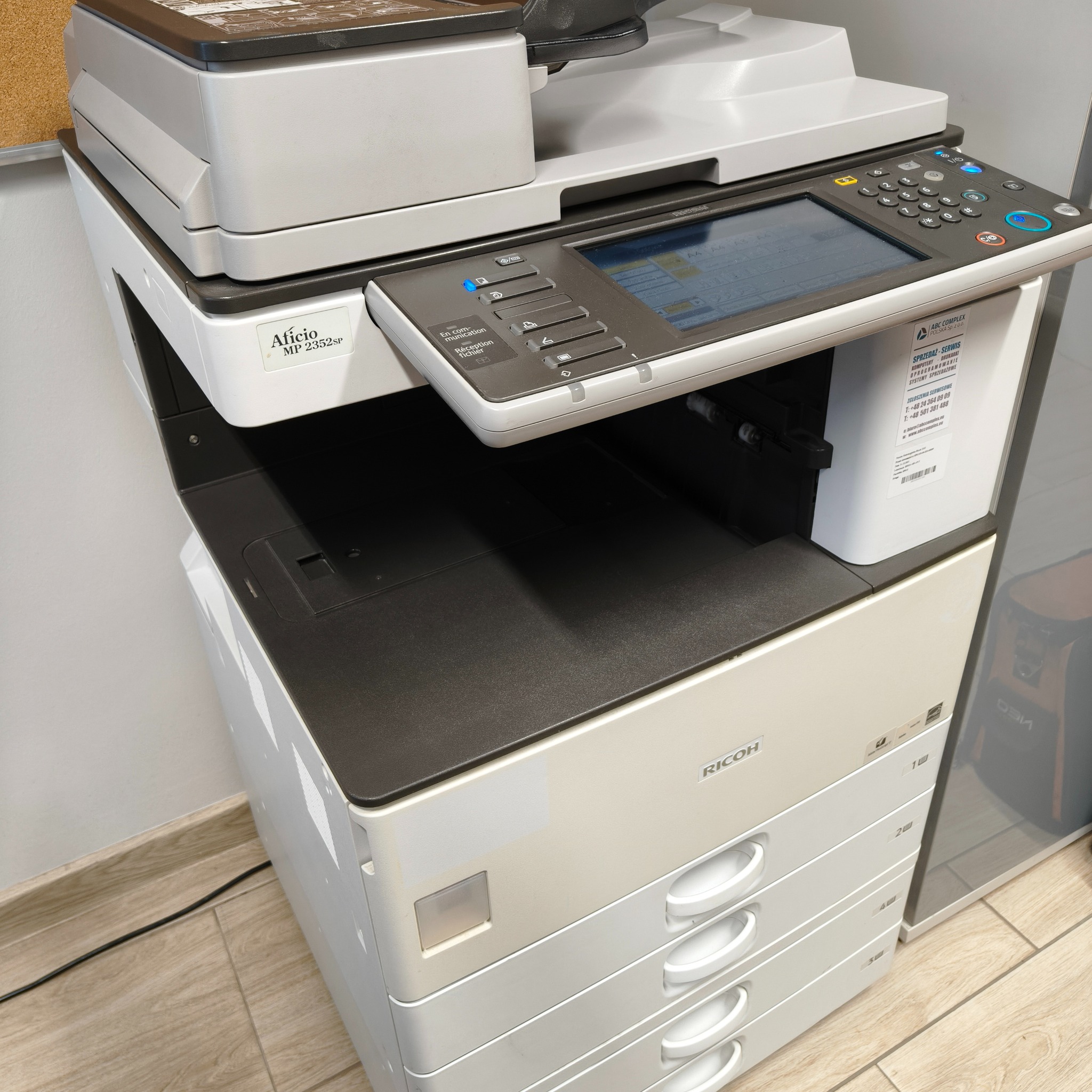 Kserokopiarka Ricoh Aficio MP 2352SP z panelem sterowania i czterema szufladami na papier, widoczna etykieta z danymi kontaktowymi serwisu ABC Complex.