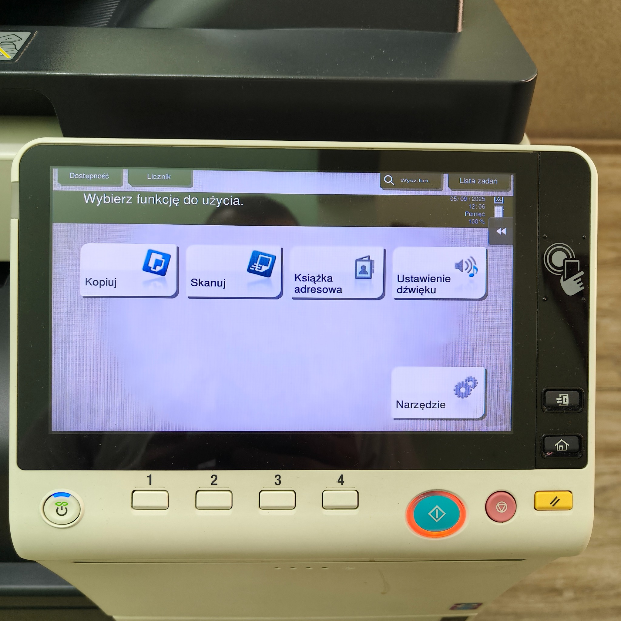 Panel dotykowy kserokopiarki z ikonami funkcji: kopiuj, skanuj, książka adresowa, ustawienie dźwięku i narzędzia. Widoczne przyciski numeryczne i funkcyjne.