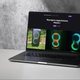 PROJSTOG Oscar Grzywa - Strony Internetowe - Laptop wyświetla stronę internetową z ofertą nagłośnienia Mielec, prezentującą sprzęt audio JBL na tle minimalistycznego, szarego tła. Widoczne menu strony i przyciski.