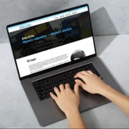 Osoba pisze na laptopie, na ekranie strona firmy EKO-STAL oferującej wywóz odpadów w Mielcu. Widoczny fragment strony 'O nas' i zdjęcia ciężarówki.