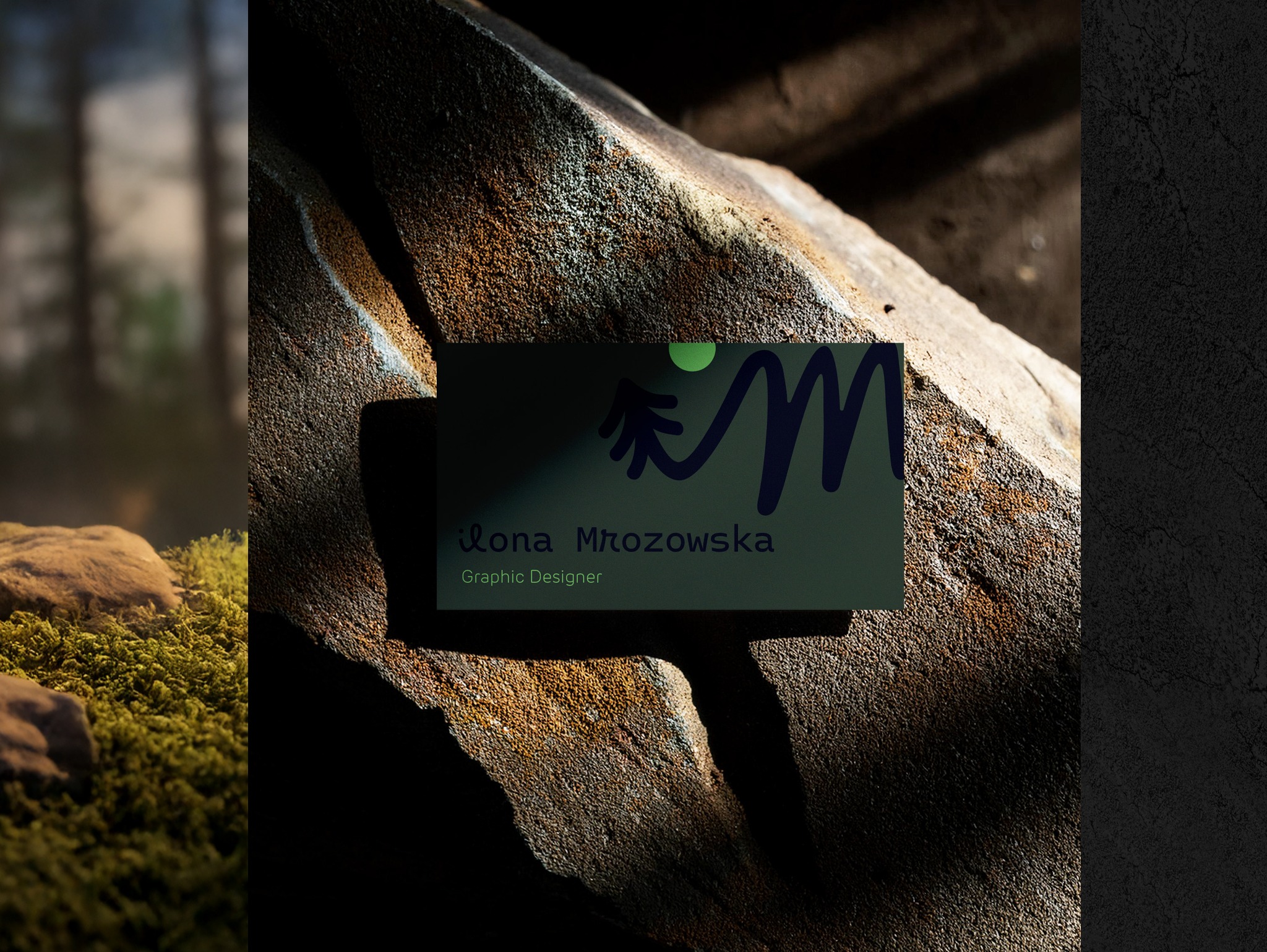 Karta wizytowa z logo i danymi kontaktowymi projektanta graficznego, umieszczona na tle kamienia z mchem, w naturalnym oświetleniu.