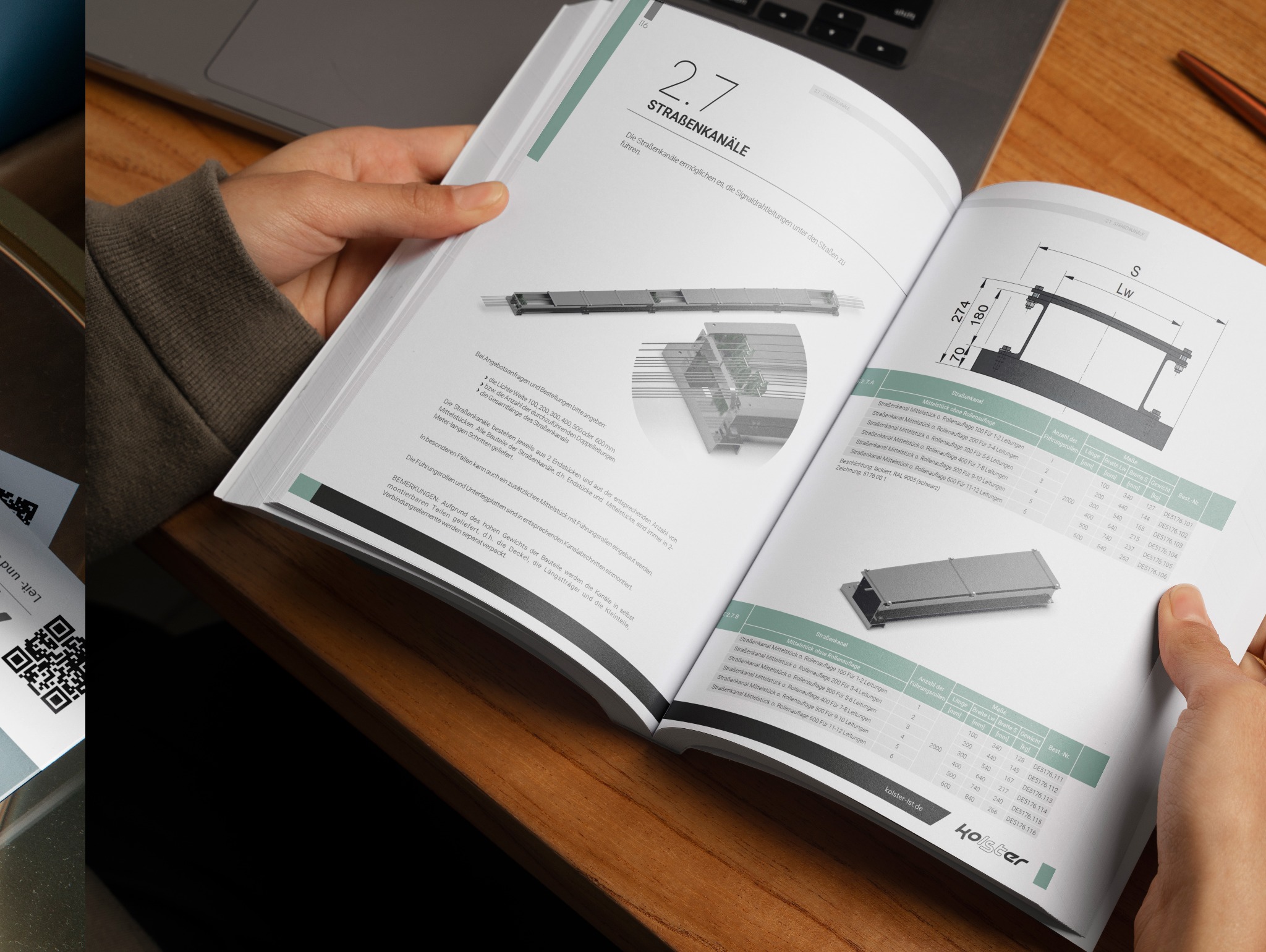 Otwarta broszura z technicznymi rysunkami i opisami kanałów kablowych, trzymana w dłoniach na tle biurka z laptopem i długopisem.