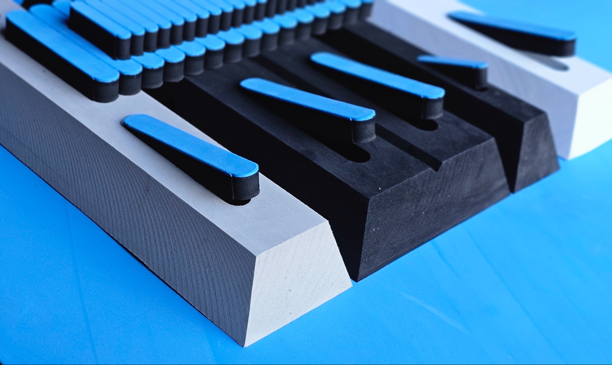 Precyzyjnie wyfrezowany, kolorowy detal z tworzywa sztucznego na niebieskim tle. Widoczne regularne kształty i gładkie powierzchnie, wykonane z dbałością o szczegóły.