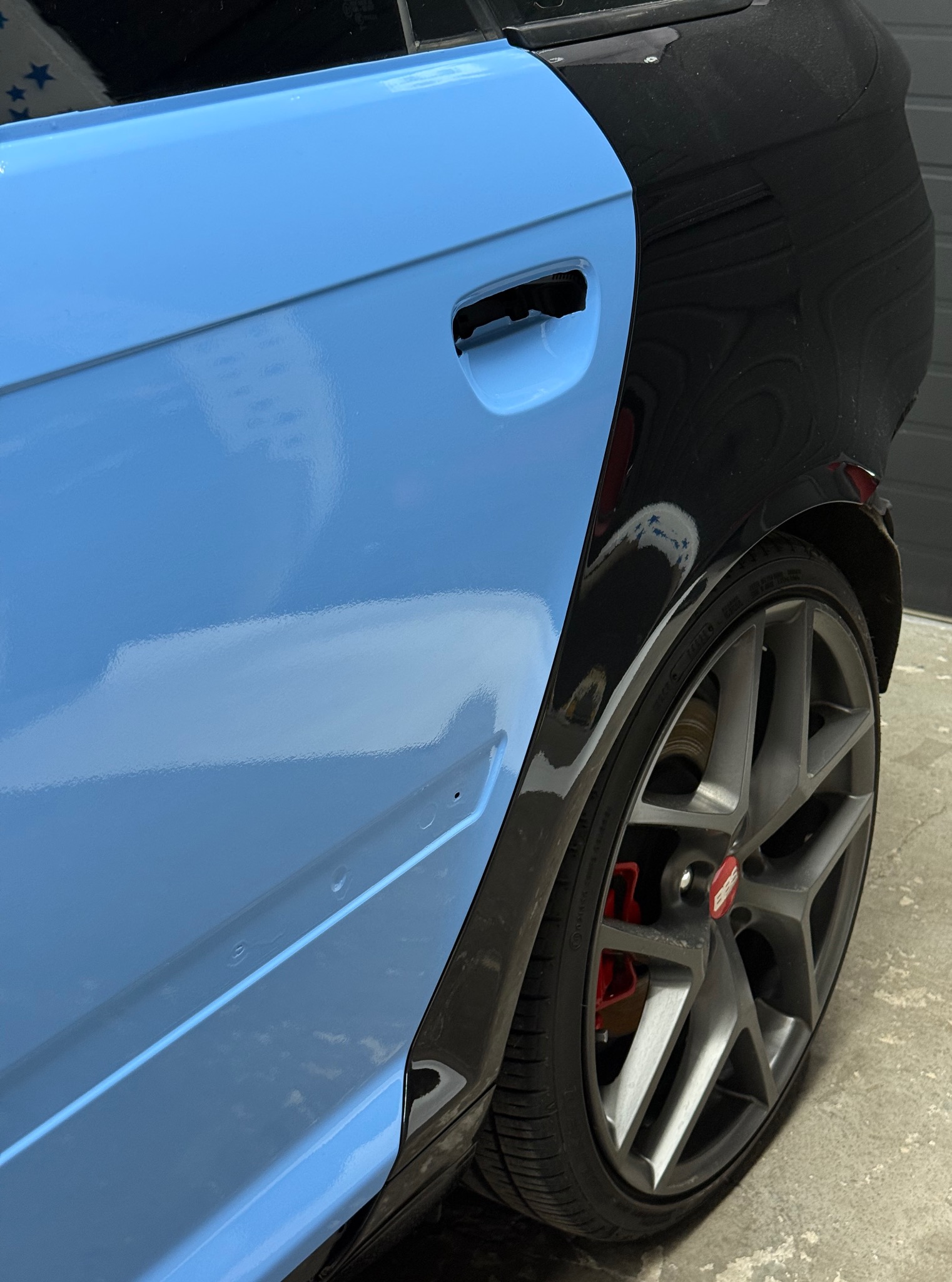 Częściowo oklejone folią w kolorze błękitnym Audi A3 8P, widoczne tylne drzwi i koło. Pozostała część karoserii w czarnym kolorze. Felgi szare, zaciski hamulcowe czerwone.