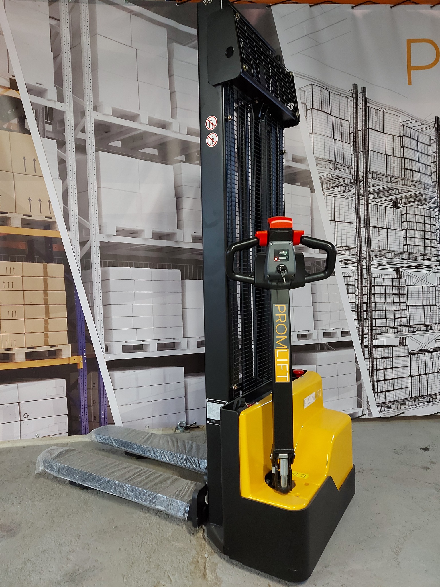Żółto-czarny elektryczny wózek paletowy PROMLIFT z folią ochronną na widłach, na tle grafiki regałów magazynowych.