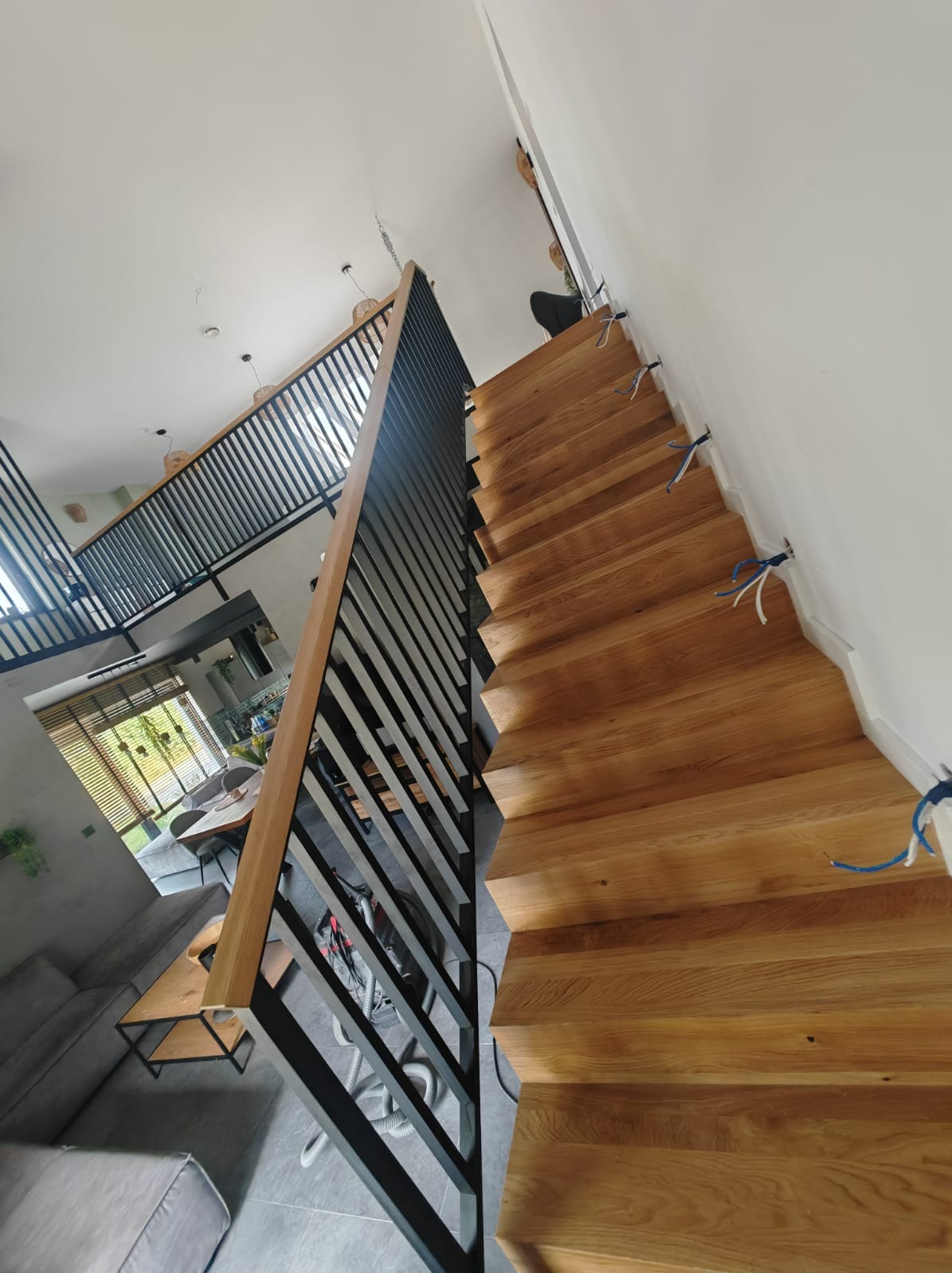 Schody dywanowe z balustradami metalowymi i drewnianą poręczą