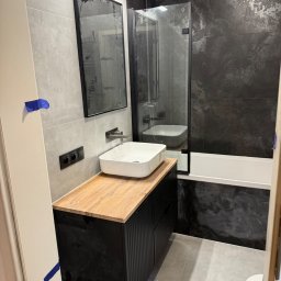 Solid bud Nazarii Kulchytskyi - Nowoczesna łazienka: szare płytki, czarna armatura, drewniany blat pod umywalką i kabina prysznicowa z czarnymi profilami. Minimalistyczny design.
