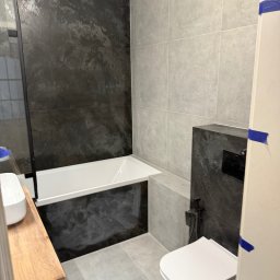 Solid bud Nazarii Kulchytskyi - Nowoczesna łazienka po remoncie: czarno-białe płytki, wanna z parawanem, podwieszana toaleta, drewniany blat umywalki i szara podłoga.