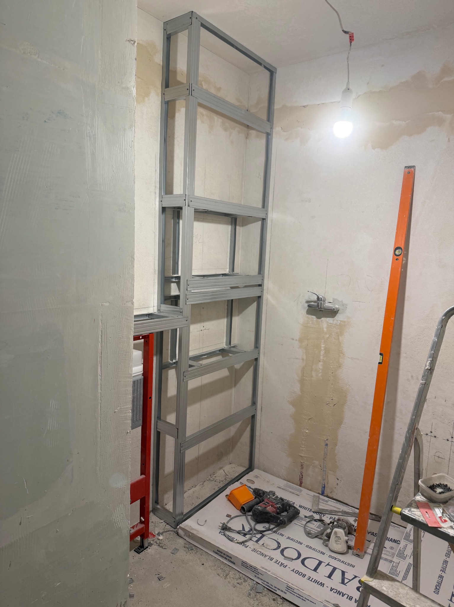 Konstrukcja z profili w trakcie prac w łazience w Warszawie. Widoczny stelaż, narzędzia i poziomica. Przygotowania do dalszych prac wykończeniowych.