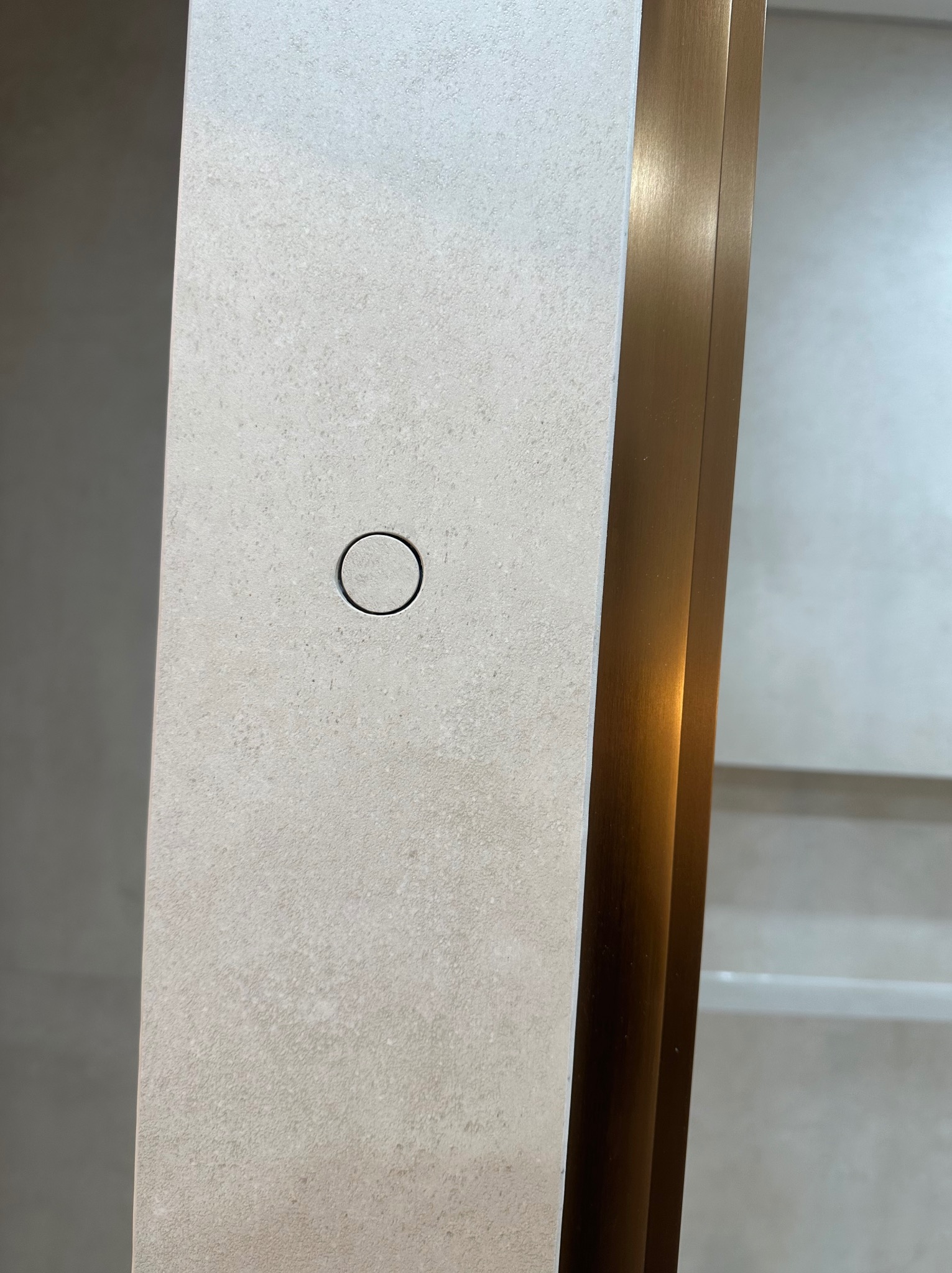 Beżowa płytka z odpływem liniowym i złotym profilem wykończeniowym. Minimalistyczny detal w nowoczesnej łazience. Delikatna faktura i subtelne oświetlenie.