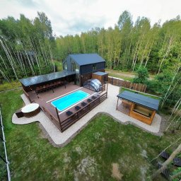 KM DESIGN SPA KRZYSZTOF KACZMARSKI - Nowoczesny dom z tarasem, basenem i jacuzzi w leśnym otoczeniu. Drewniana zabudowa, oświetlenie girlandami, elegancki design.