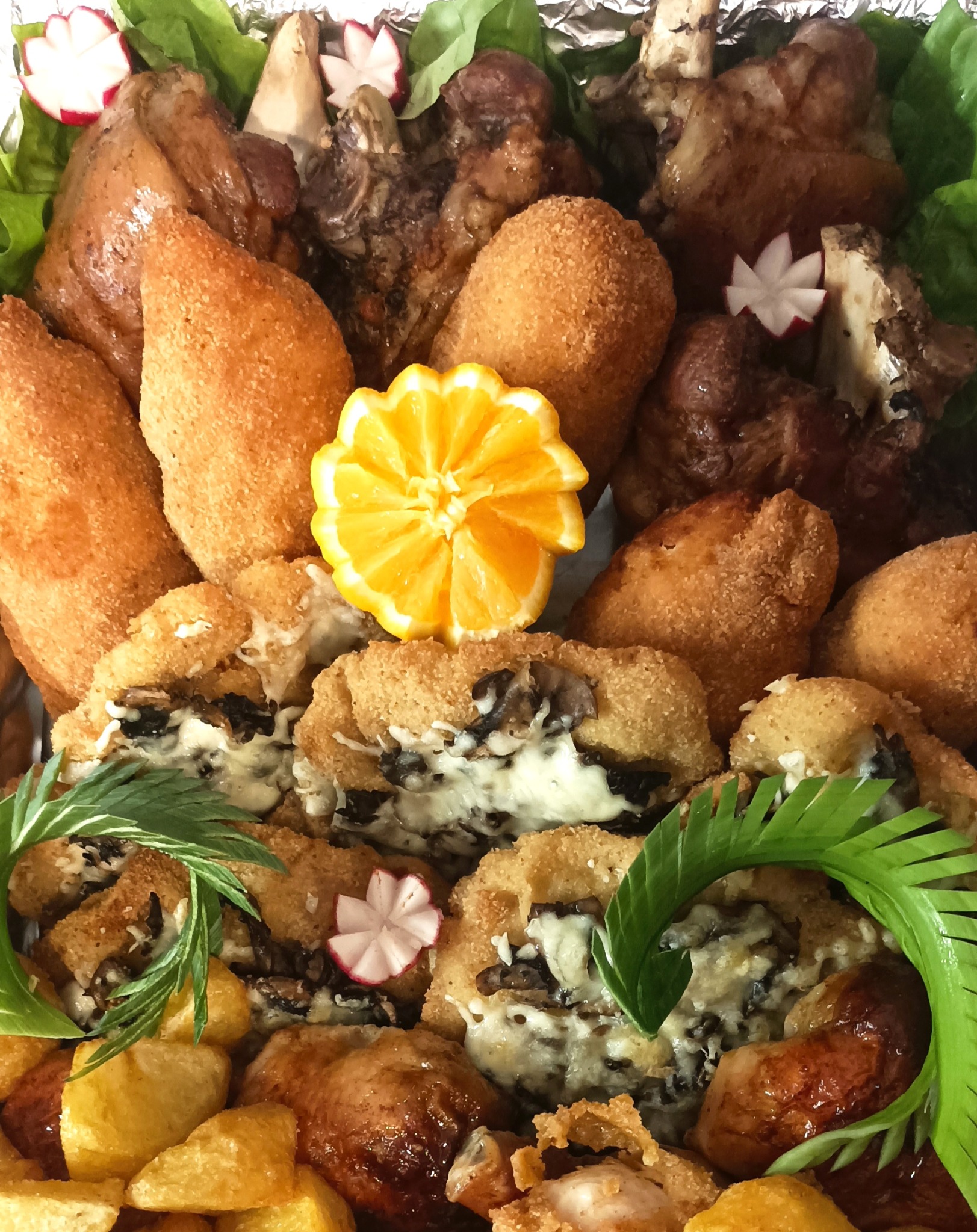 Bogato zdobiona patera z różnorodnymi przekąskami: krokiety, mięsa, warzywa i pomarańcza, tworząca apetyczną kompozycję idealną na przyjęcie.