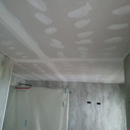 Oskar Ancypa - Sufit z płyt kartonowo-gipsowych, z widocznymi łączeniami i szpachlowaniem, przygotowany do dalszych prac wykończeniowych. Ściany surowe, zabezpieczone folią.