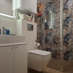 Łazienka po kładzeniu płytek podłogowych i ściennych, zabudowie spłuczki toaletowej, montażu odpływu liniowego, kabiny prysznicowej, lustra, lamp, szafek i grzejnika.