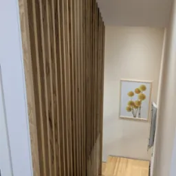 Ściana z lameli na klatce schodowej. Schody jesionowe