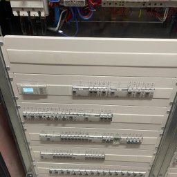 Michał Danowski - Rozdzielnia elektryczna z bezpiecznikami, okablowaniem i licznikiem zużycia energii, widok od dołu, oświetlenie górne.