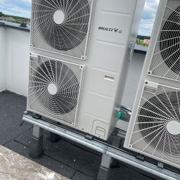 Michał Danowski - Zewnętrzne jednostki klimatyzacji LG Multi V 8 na dachu budynku, widoczne wentylatory i elementy montażowe. Tło stanowią budynki i niebo.