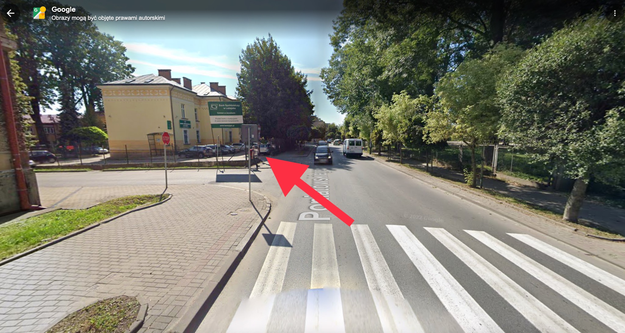 Zewnętrzny widok budynku Banku Spółdzielczego w Leżajsku z ulicy, z przejściem dla pieszych i znakiem STOP, sfotografowany w słoneczny dzień.