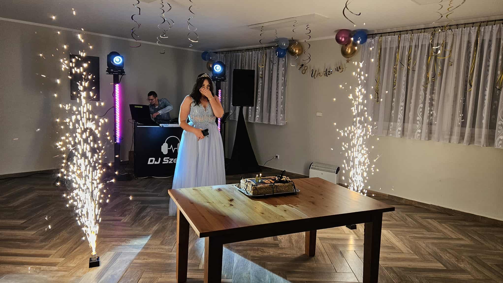 Urodzinowa osiemnastka: zaskoczona dziewczyna w tiarze, tort ze świeczkami, DJ, nagłośnienie i fontanny iskier tworzą radosną atmosferę imprezy.