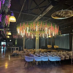 ELEKTROINVEST Sp. z o.o. - Eleganckie oświetlenie restauracji z wiszącymi lampami w kształcie kwiatów i rzędami krzeseł, tworzące unikalny klimat wnętrza.