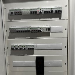 ELEKTROINVEST Sp. z o.o. - Rozdzielnica elektryczna z wyłącznikami, opisana sekcjami: 'Ogranicznik przepięć', 'Rezerwa', 'Sauna Fińska', z datą wykonania Luty 2025.