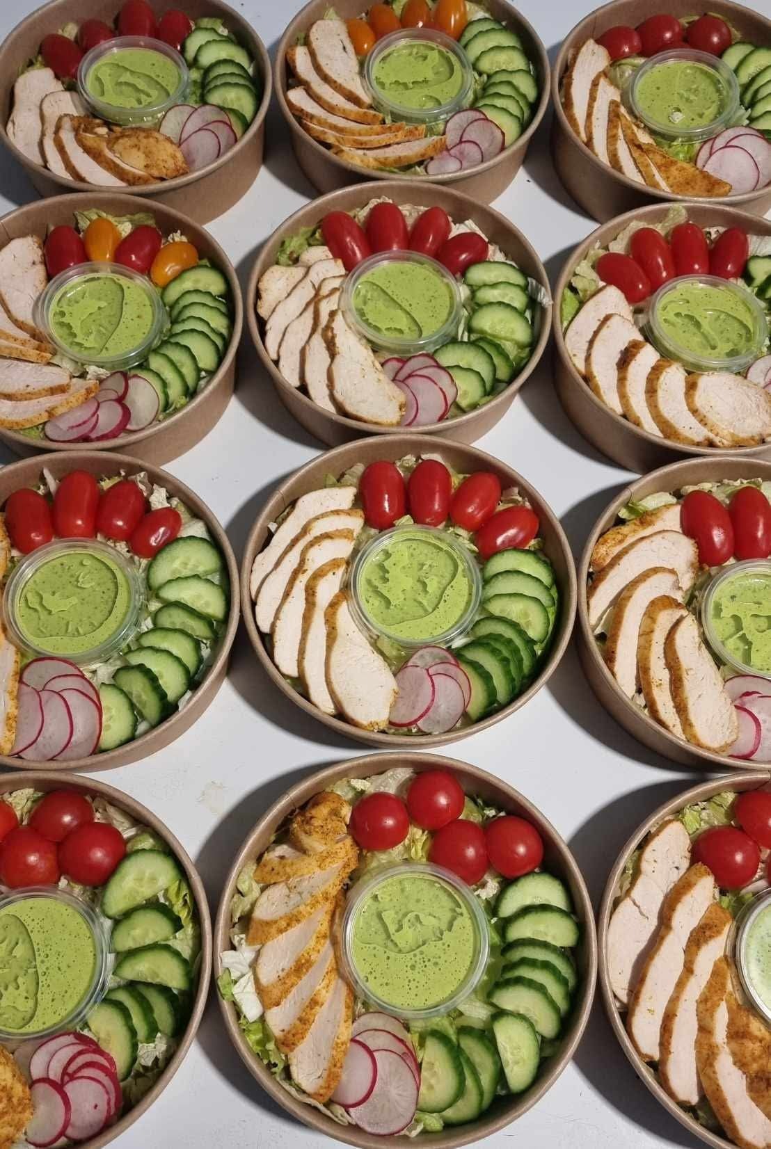 Zestaw 9 porcji sałatek w okrągłych, kartonowych miskach. Sałatka z kurczakiem, pomidorkami, ogórkiem, rzodkiewką i sosem guacamole. Catering dietetyczny.