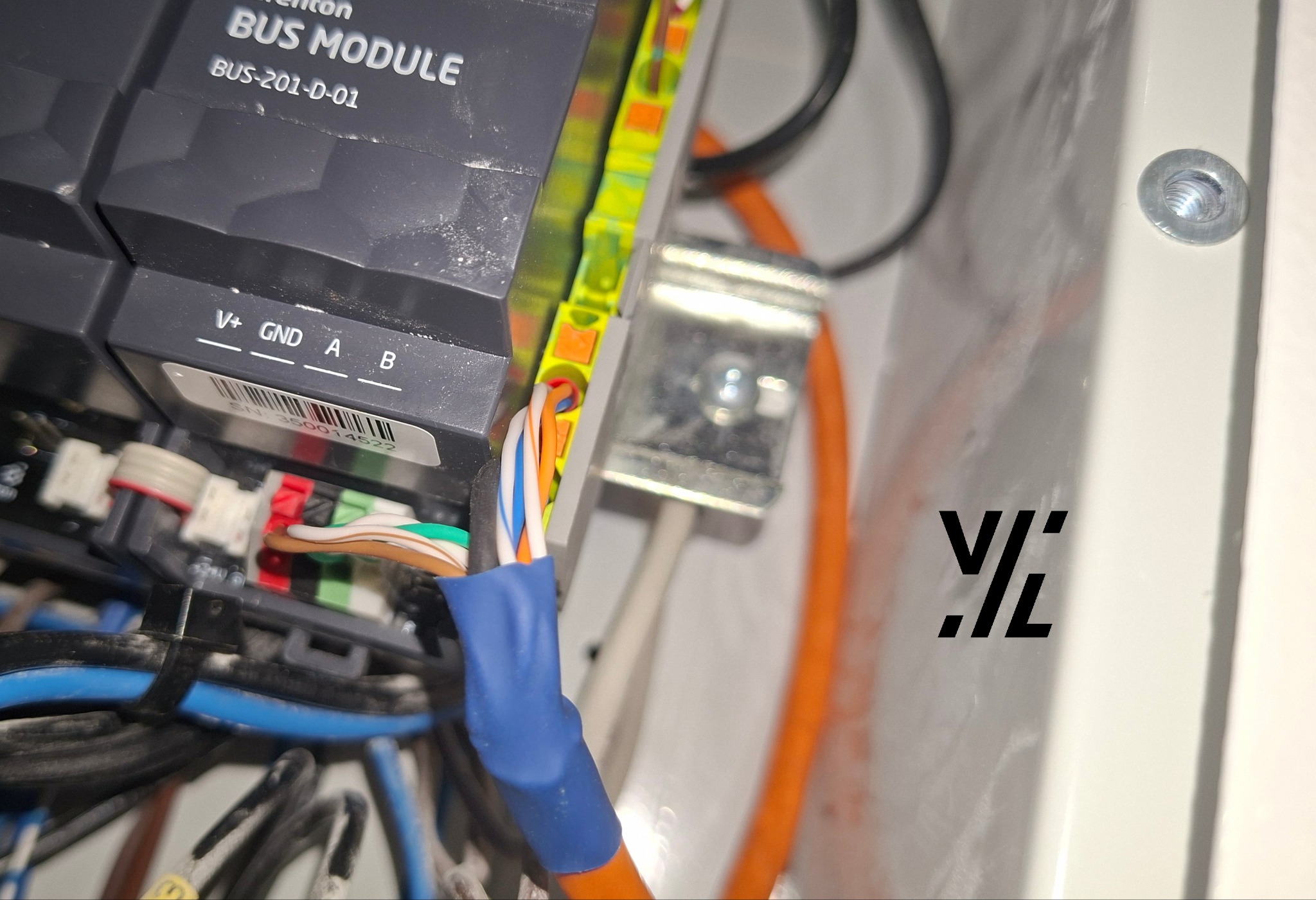 Detale połączeń modułu BUS-201-D-01 z kolorowymi przewodami w skrzynce rozdzielczej. Widoczne złącza V+, GND, A, B oraz zabezpieczone kable.