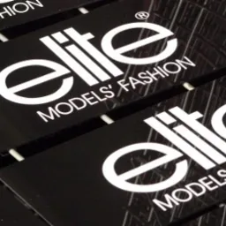 Czarne, błyszczące naklejki z białym logo 'Elite Models' Fashion' ułożone w rzędzie, widoczne odbicia światła.