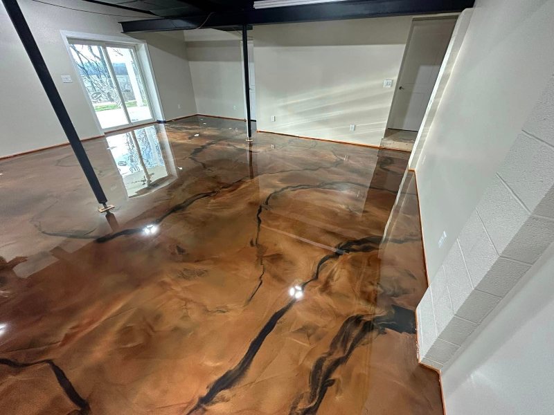 Błyszcząca, miedziano-brązowa posadzka żywiczna z czarnymi żyłkami, odbijająca światło w nowoczesnym wnętrzu. Widoczne okno przesuwne i fragment ściany.