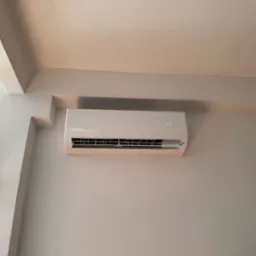 Biały klimatyzator Rotenso zamontowany na ścianie, widoczny wyświetlacz z temperaturą 17 stopni, minimalistyczny design, neutralne tło.