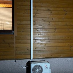 Wenturo Sp. z o. o. - Zamontowana jednostka zewnętrzna klimatyzacji Rotenso przy drewnianej ścianie domu, z widoczną instalacją odprowadzającą skropliny. Ujęcie nocne.