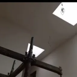 Świeżo otynkowane wnętrze z widocznymi rusztowaniami, oświetlone światłem z okien dachowych. Ściany gładkie, przygotowane do dalszych prac wykończeniowych.