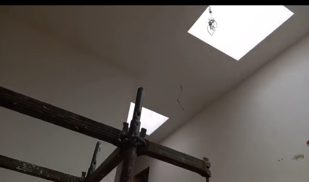 Świeżo otynkowane wnętrze z widocznymi rusztowaniami, oświetlone światłem z okien dachowych. Ściany gładkie, przygotowane do dalszych prac wykończeniowych.