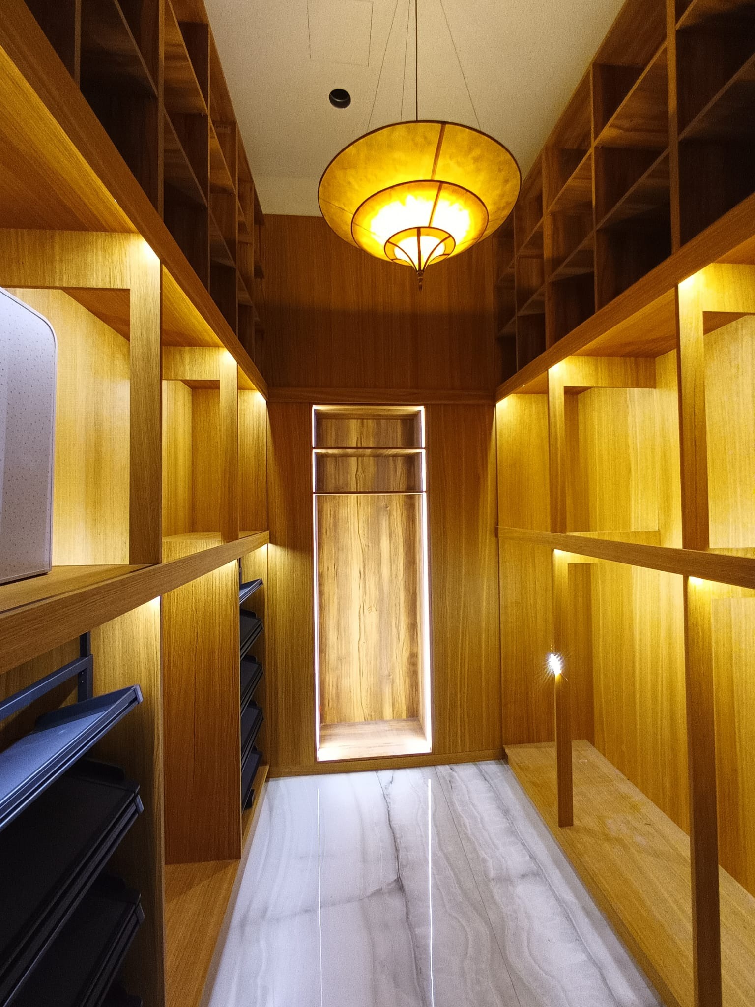 Nowoczesna garderoba z drewna z oświetleniem LED, marmurowa podłoga i oryginalna lampa sufitowa. Projekt wnętrza z półkami i wnękami.