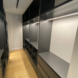 WOBO studio Wojciech Borawski - Nowoczesna, szara garderoba z oświetleniem LED i półkami wnękowymi, widok z perspektywy wnętrza, jasna drewniana podłoga, minimalistyczny design.