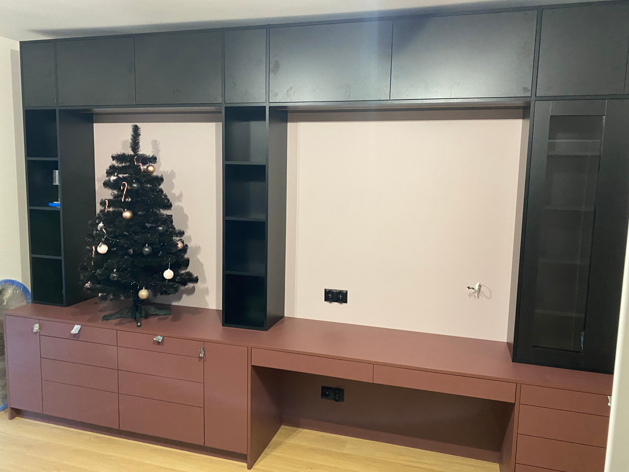 Kompleksowa zabudowa meblowa w odcieniach brązu i czerni, z biurkiem i szafkami wiszącymi, uzupełniona o świąteczną dekorację, tworząca spójną przestrzeń.