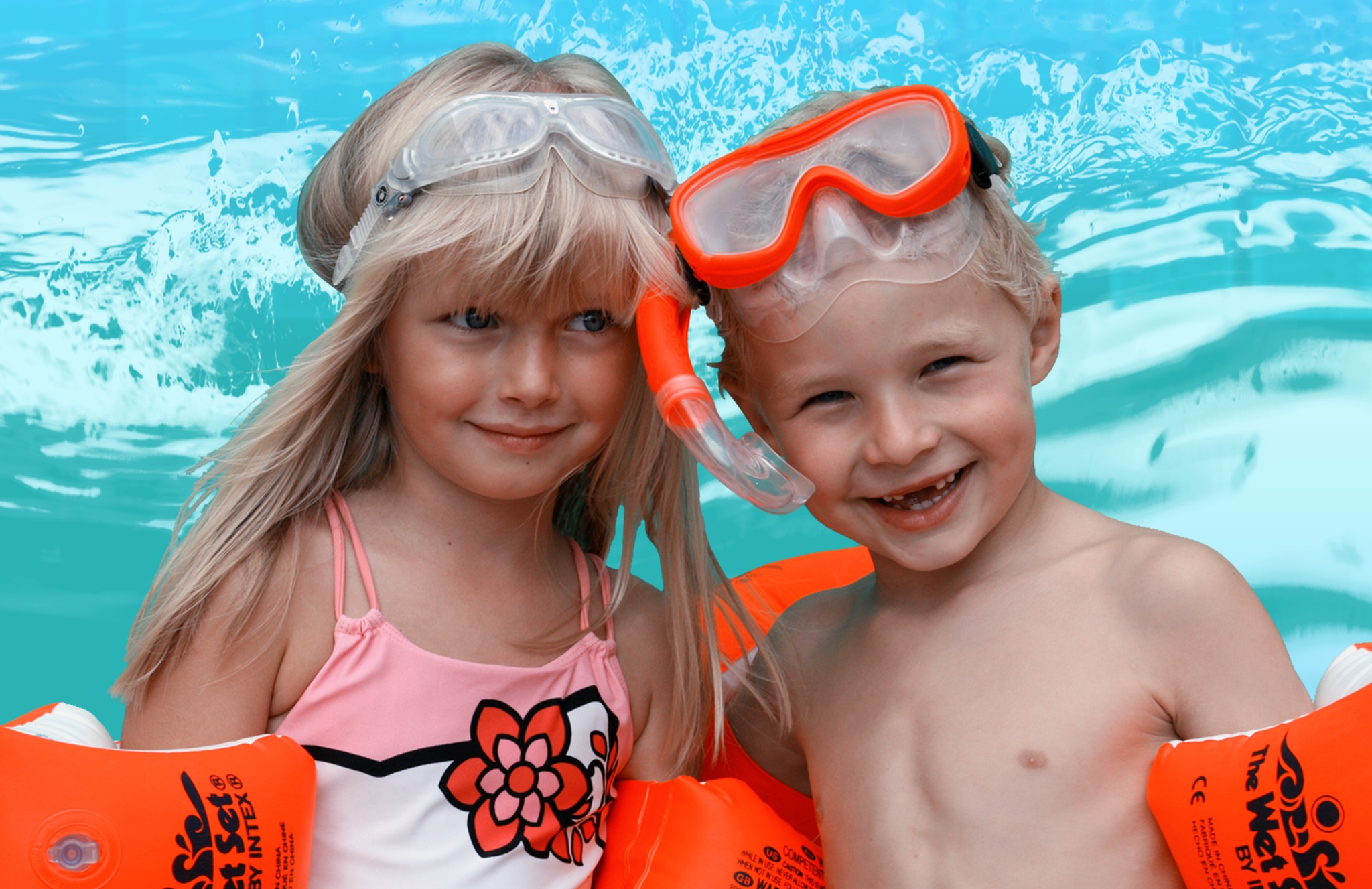 Uśmiechnięte dzieci w wodzie z maskami i rękawkami do pływania Intex. Dziewczynka w różowym stroju kąpielowym z kwiatkiem. Radosna atmosfera nauki pływania.
